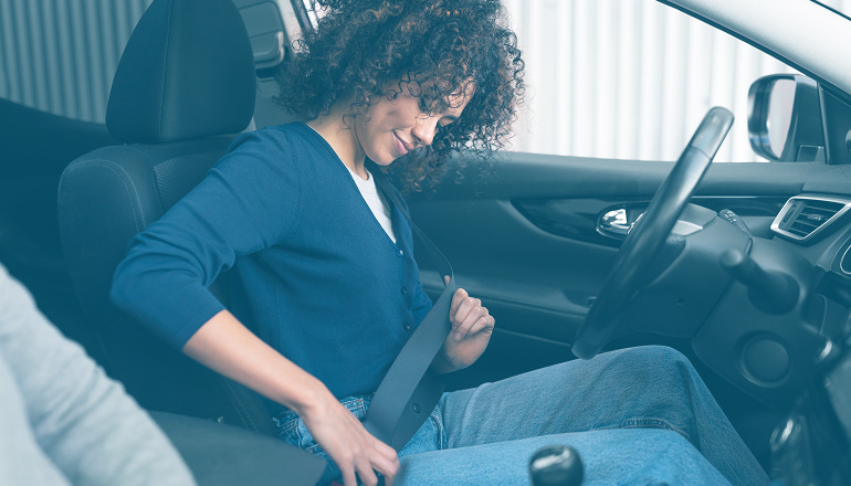 mujer abrochándose el cinturon de seguridad del coche para evitar multas y asgurarse la indemnizacion en caso de accidente de tráfico